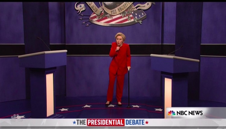 Hillary Clinton (Kate McKinnon) entra de bengala e tossindo muito no debate, zombando de sua recente pneumonia. (Foto: Reprodução)